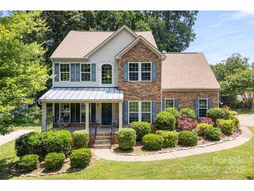 Charming two-story home boasts manicured landscaping, stone accents, and inviting covered front porch at 329 Squirrel Ln, Clover, SC 29710