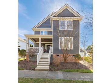 Charming two-story home with gray siding, brick foundation and welcoming front porch with white banister and steps at 13725 Mallory Baches Ln, Huntersville, NC 28078