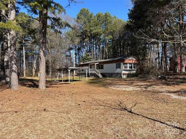 Exterior view of home with car port and surrounded by trees in a wooded area at 1406 Ratchford Dr, Dallas, NC 28034