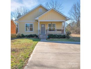 Charming yellow cottage with a cozy front porch and well-manicured lawn on a sunny day at 293 Blanche Cir, Rock Hill, SC 29730