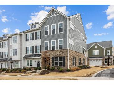 Beautiful townhome featuring a brick facade, gray siding, and black shutters against a backdrop of a blue, partly cloudy sky at 1037 Naples Dr, Davidson, NC 28036