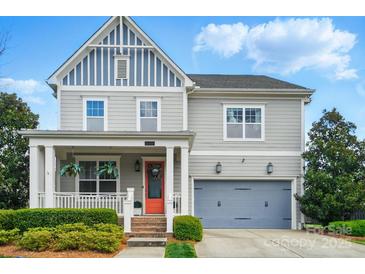 Charming two-story home with gray siding, an orange front door, a covered porch, and a two-car garage at 15307 Country Lake Dr, Pineville, NC 28134