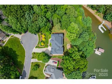 Aerial shot showcases property's lush landscaping, circular driveway, and serene location nestled among mature trees and lake access at 228 Wildwood Cove Dr, Mooresville, NC 28117