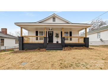 Charming home featuring a covered front porch, classic black shutters, and a well-maintained yard at 612 Miller St, Kannapolis, NC 28081