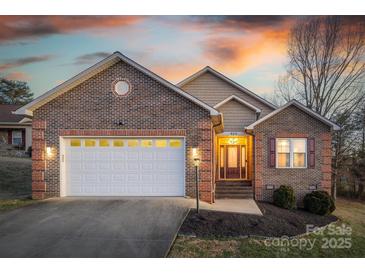 Charming brick home with a two-car garage, landscaped yard, and warm exterior lighting at 924 41St Avenue Ne Dr, Hickory, NC 28601