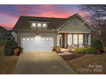 Charming home with a two-car garage, covered porch with rocking chairs, and well-maintained landscaping at 113 Artisan Ct, Mooresville, NC 28117