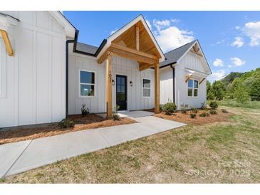 Charming front porch with natural wood beams, a black front door, and manicured landscaping at 1037 Dameron Rd, Bessemer City, NC 28016