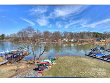 Expansive lake view featuring a dock, boat lifts, and canoes on a sunny day with blue skies and scattered clouds at 107 Pier 33 Dr # 103, Mooresville, NC 28117