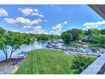 Beautiful waterfront view with boat dock, lush green lawn, and colorful kayaks perfect for outdoor lake living at 107 Pier 33 Dr # 103, Mooresville, NC 28117