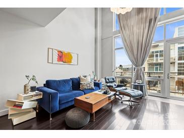 Bright living room with hardwood floors, high ceilings, modern furniture, and an outdoor balcony at 1133 Metropolitan Ave # 318, Charlotte, NC 28204
