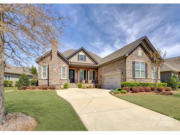 Charming stone home with manicured lawn and long driveway leading to attached two car garage at 14830 Creeks Edge Dr, Charlotte, NC 28278