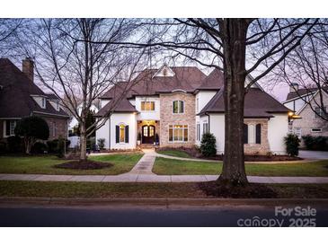 Elegant home featuring a stone and stucco facade, manicured lawn, and professional landscaping at 7924 Pemswood St, Charlotte, NC 28277