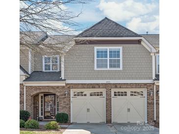 Charming townhome featuring a brick facade, a welcoming entrance, and a two-car garage with carriage-style doors at 8513 Loxton Cir, Charlotte, NC 28214