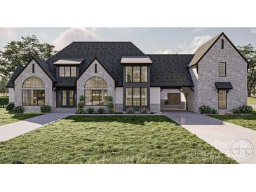 A stunning view of a stone-clad house with a porte-cochere and well-manicured lawn showcasing architectural design at 1057 Maxwell Ct # 13, Marvin, NC 28173