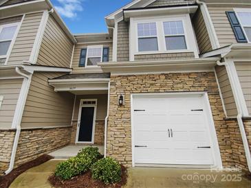 Charming townhome featuring stone accents, a one-car garage, and a welcoming front entrance at 8619 Harris Lake Ln, Charlotte, NC 28269