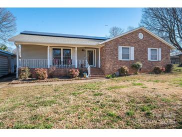 Charming brick and siding home with a cozy front porch, solar panels, and well-manicured landscaping at 9026 Longview Dr, Charlotte, NC 28214
