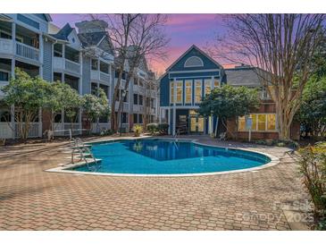 Community pool with a brick surround and several apartment buildings in the background at 525 N Graham St # 3B, Charlotte, NC 28202