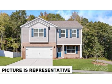 Charming two-story home featuring a brick facade, attached garage, and beautifully landscaped front yard at 122 Woodhall Way, Troutman, NC 28166