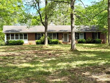 Charming single-story brick home featuring a well-manicured lawn and mature trees providing ample shade at 1330 College Ave, Shelby, NC 28152