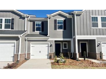 Charming two-story townhouse featuring a one-car garage, gray siding, and brick accents for added curb appeal at 1748 Braemar Village Dr, Monroe, NC 28110