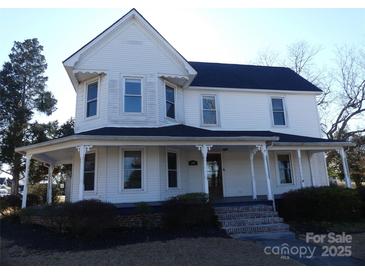 Charming two-story home featuring a welcoming wrap-around porch and mature landscaping at 201 W Rice St, Landis, NC 28088