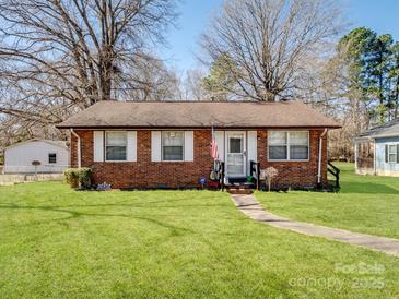 Charming brick home featuring a well-manicured front yard with a paved walkway and an American flag at 506 Bond St, Cherryville, NC 28021