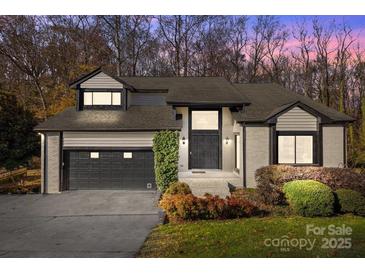 Charming gray brick home with a two-car garage, black trim, mature landscaping and well-maintained lawn at 9334 Hunting Ct, Matthews, NC 28105