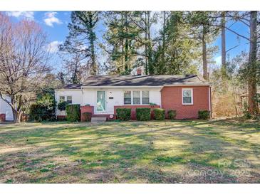Charming single-story home with a brick and white facade, surrounded by lush greenery and mature trees at 1001 E 8Th Ave, Gastonia, NC 28054