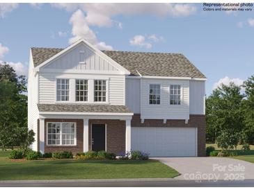 This two-story home boasts a brick and white facade, attached two-car garage, and is surrounded by a lush green lawn at 1201 Blackburn Cir, Edgemoor, SC 29712