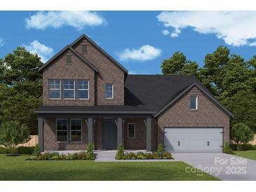 Handsome two-story brick home with a covered porch, attached two car garage, and professionally landscaped front yard at 13130 Macon Hall Dr, Mint Hill, NC 28227