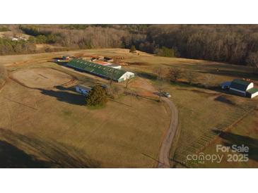 Expansive aerial view of horse farm featuring barn, riding ring, pastures, and outbuildings amid rolling hills and mature trees at 2137 Old Latter Rd, Newton, NC 28658
