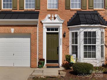 Charming brick home featuring a decorative doorway, black metal awning, and attached garage at 4022 Carl Parmer Dr, Harrisburg, NC 28075