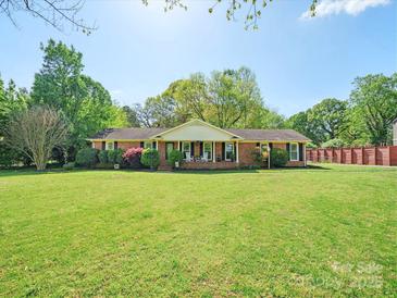 Charming one-story brick home featuring a covered front porch and a lush green lawn at 6349 Lebanon Rd, Mint Hill, NC 28227