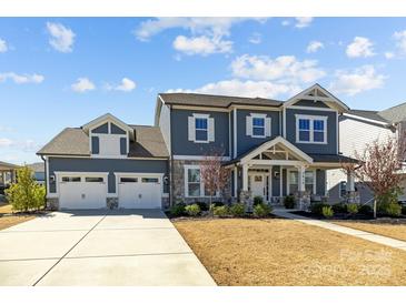 Charming two-story home featuring a two-car garage, stone accents, and landscaped front yard at 2419 Paddlers Cove Dr, Clover, SC 29710