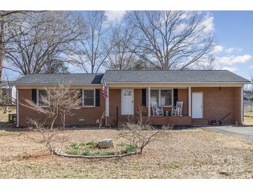 Charming brick home with a covered front porch, rocking chairs, and an American flag at 437 Valley St, Stanley, NC 28164