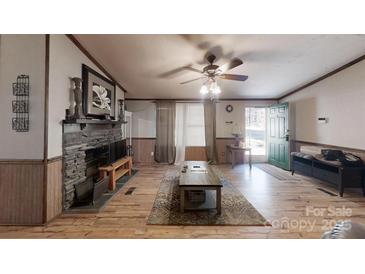 Inviting living room featuring a stone fireplace, ceiling fan, and wood-look floors at 5124 Gates Dr, Denver, NC 28037