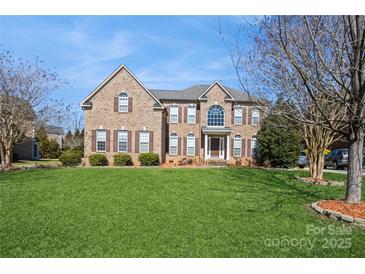 Traditional brick home featuring a manicured lawn, mature trees, and a welcoming entrance at 1116 Crooked River Dr, Waxhaw, NC 28173