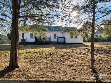 A backyard featuring a two-story home with a black deck, surrounded by a partially grassy yard at 200 Hillcrest Ave, Hickory, NC 28601