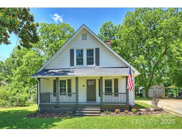 Charming two-story home with a covered front porch, American flag, and landscaped yard at 237 Mcneely Ave, Mooresville, NC 28115