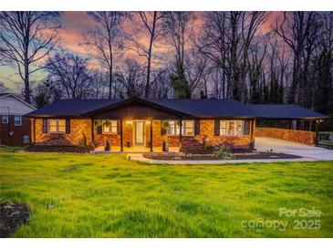 Charming brick home featuring a covered front porch, beautiful lawn, and convenient carport at 308 Dakota St, Kannapolis, NC 28083