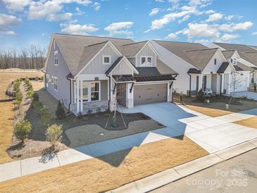 New construction featuring gray siding, stone accents, a two-car garage, and beautifully landscaped front yard at 1113 Idyllic Ln, Waxhaw, NC 28173