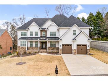 Elegant stucco home with a dark roof, two-car garage, stone accents, and manicured lawn at 15818 Sparrowridge Ct, Charlotte, NC 28278