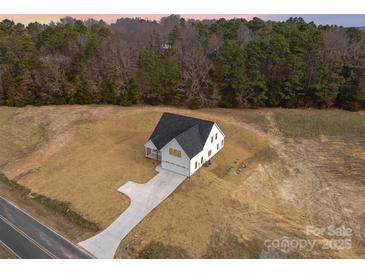 New construction home featuring a paved driveway and surrounded by an undeveloped landscape and lush wooded area at 2095 Tite Rd, Stanfield, NC 28163