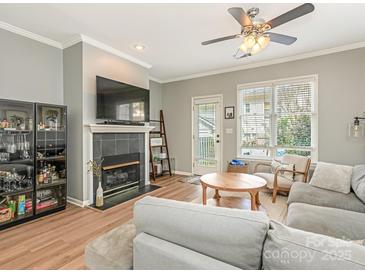 Cozy living room features a fireplace with tile surround, a large TV, and a ceiling fan at 2658 Dilworth Heights Ln, Charlotte, NC 28209