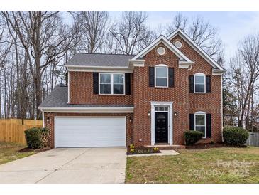 Charming two-story brick home with a well-manicured lawn, attached garage and a black front door at 10211 Ridgewell Ct, Charlotte, NC 28215