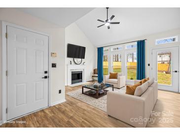 Bright living room features a fireplace, large windows, and vaulted ceilings at 10211 Ridgewell Ct, Charlotte, NC 28215