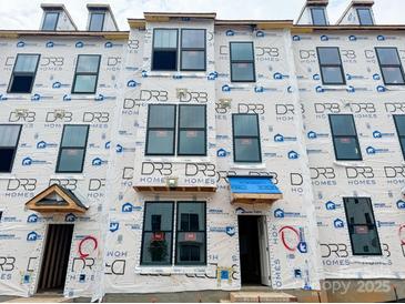 View of new construction townhome with Barricade wrap, dormer windows, and covered entryway at 15332 Ballancroft Pkwy # 17, Charlotte, NC 28277