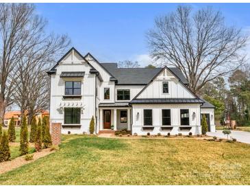Striking two-story white home with black trim, complemented by a lush lawn and tasteful landscaping at 16112 Terry Ln, Huntersville, NC 28078