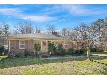 Charming brick home with a well-maintained lawn and mature landscaping under a beautiful blue sky at 3901 Starmount Ave, Charlotte, NC 28269