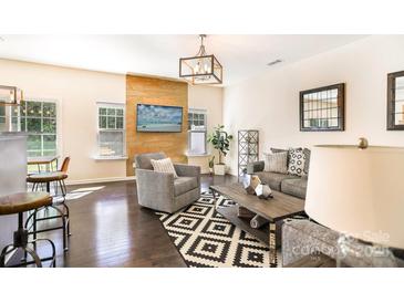 Bright living room featuring hardwood floors, stylish furniture, a modern light fixture, and a beautiful accent wall at 13529 Browhill Ln, Charlotte, NC 28278